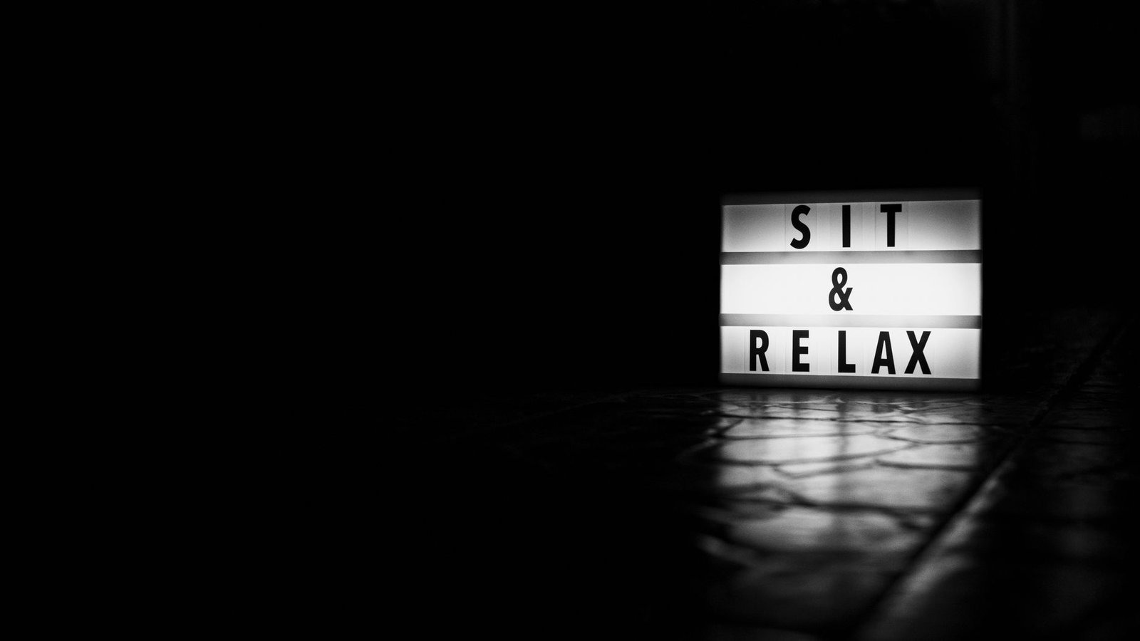 A light box with 'Sit & Relax' on a reflective floor, emphasizing calmness.