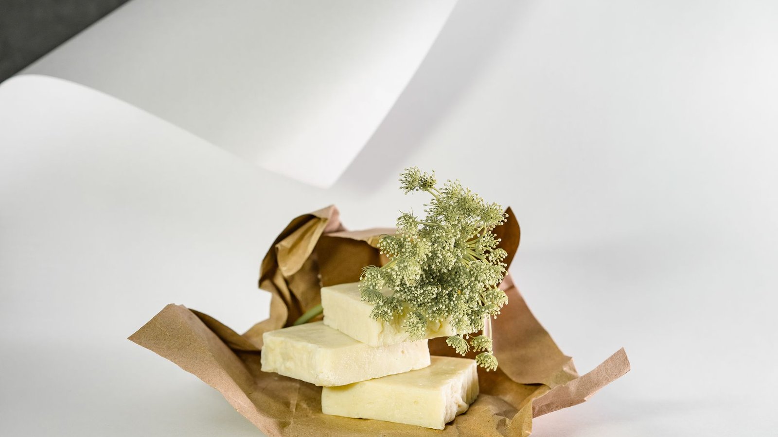 Handmade soap bars wrapped in paper with dried flowers on a clean white sweep, the lit-and-styled first frame an Etsy listing needs at thumbnail size