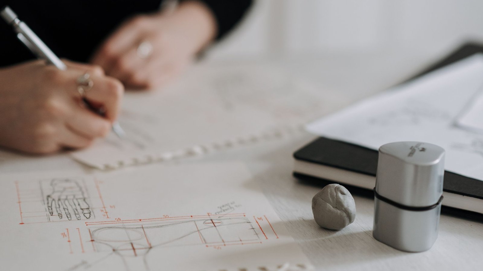Designer sketching chart panels in a notebook while planning an infographic layout before merging