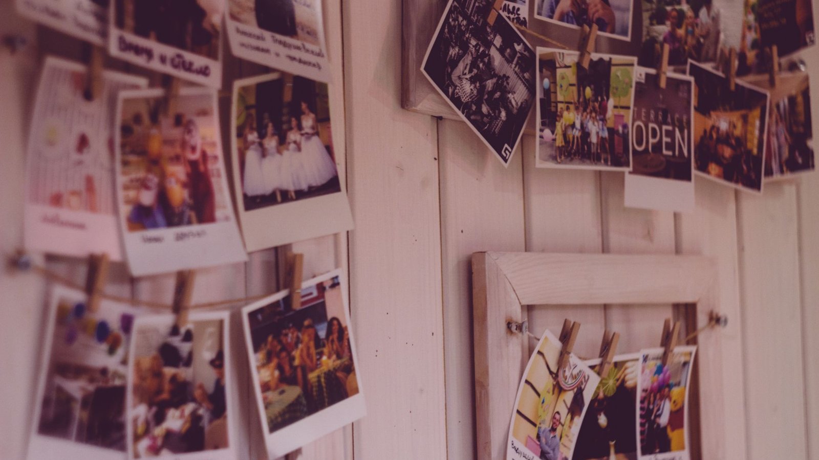 Collection of vintage Polaroid photos clipped to a wooden wall indoors.