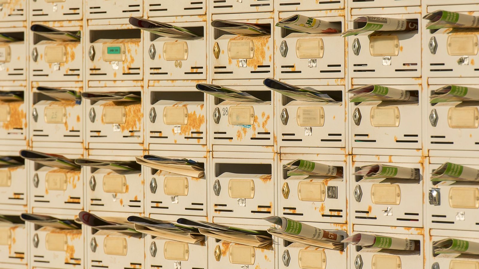 A wall of metal pigeonhole mailboxes with post rolled into every slot, the crowded inbox a newsletter header has to stand out in