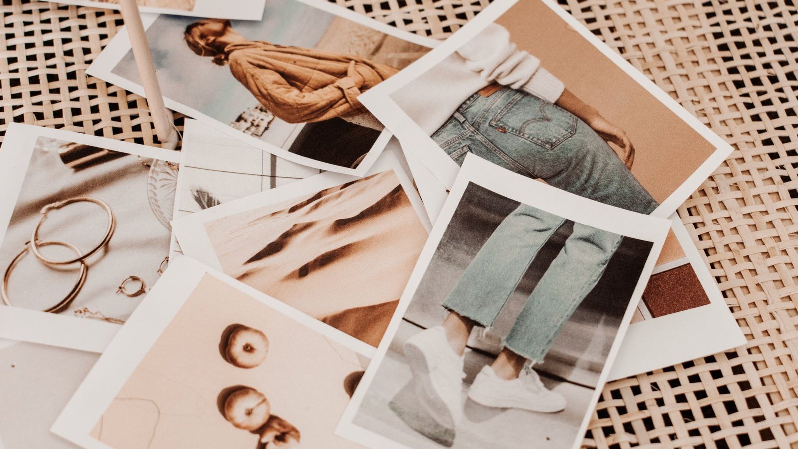Printed travel photos scattered in an overlapping pile on a woven mat, the raw material a multi-destination collage has to arrange into a grid